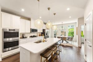 a kitchen with white cabinets and a kitchen island with bar stools at Ashburn 4-BR Homestay Close to Dulles & METRO in Brambleton