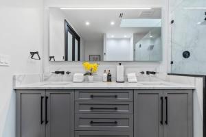 Baño blanco con 2 lavabos y espejo en Top of The Hill Luxury Clarendon 4-BR Homestay, en Arlington