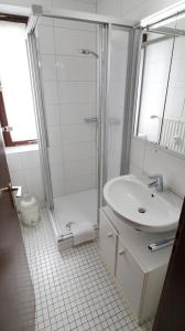 uma casa de banho branca com um chuveiro e um lavatório. em Fewo Blumbach Nr 4, Schluchsee, Feldberg em Schluchsee