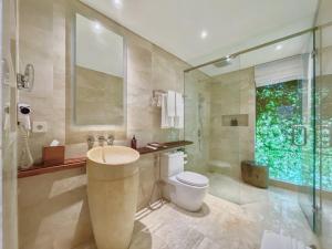 a bathroom with a toilet and a glass shower at Candi Beach Resort & Spa in Candidasa