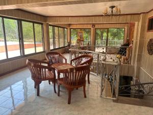 a dining room with a table and chairs and windows at ไททำดี โฮมสเตย์ Taitam-D Homestay in Ta Phraya