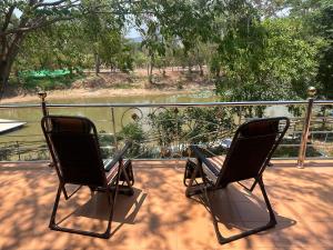 duas cadeiras num alpendre com vista para um rio em ไททำดี โฮมสเตย์ Taitam-D Homestay em Ta Phraya
