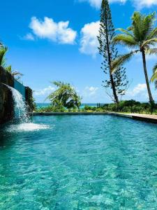 a swimming pool with a waterfall and palm trees at Summer beachfront apartment in Belle Mare