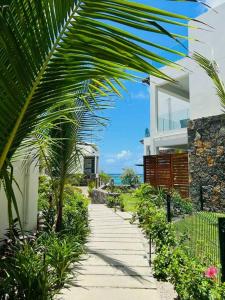 a palm tree in front of a house with a walkway at Summer beachfront apartment in Belle Mare