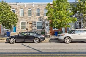 two cars parked in front of a brick building at Charm City Homestay in Washington Village in Baltimore