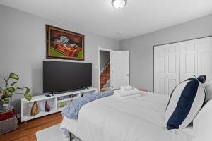 a white bedroom with a large bed with a flat screen tv at Short Drive to Capitol Hill-Convenient MD Homestay in Capitol Heights