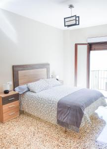 Un dormitorio con una cama y una cómoda y una ventana. en Casa de los Abuelos, en Úbeda