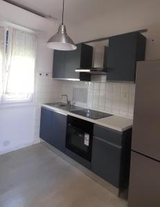 a kitchen with black cabinets and a sink and a window at SanBart Villetta con Giardino in San Bartolomeo al Mare