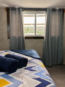 Schlafzimmer mit einem Bett und einem Fenster mit Vorhängen in der Unterkunft Alta Terra Hospedajes in Quetzaltenango