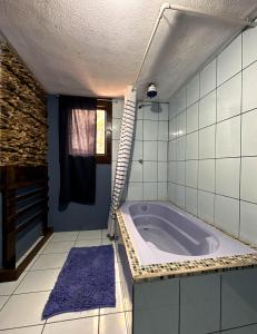 La salle de bains est pourvue d'une baignoire et d'un tapis violet. dans l'établissement Alta Terra Hospedajes, à Quetzaltenango