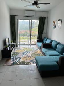 sala de estar con sofá azul y ventana grande en Danau Homestay en Bandar Puncak Alam