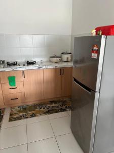 La cuisine est équipée d'un réfrigérateur en acier inoxydable et de placards en bois. dans l'établissement Danau Homestay, à Bandar Puncak Alam