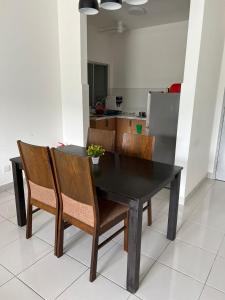 une table à manger noire avec des chaises et une cuisine dans l'établissement Danau Homestay, à Bandar Puncak Alam