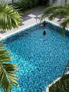une personne nageant dans une grande piscine bleue dans l'établissement Danau Homestay, à Bandar Puncak Alam