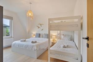 ein weißes Schlafzimmer mit einem Etagenbett und einem Fenster in der Unterkunft Maison Malo in De Haan