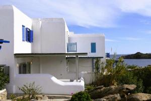 a white house with blue windows and a balcony at Bluewave Lux house in Ornos