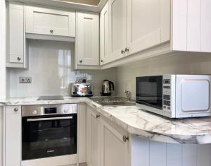 a white kitchen with white cabinets and a counter top at The Buckingham Studio in Glasgow