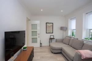 a living room with a couch and a flat screen tv at Bright Central Flat with Balcony and Free Parking in Glasgow