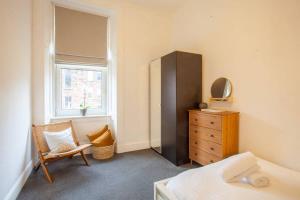 a bedroom with a bed and a dresser and a window at Stunning 2 bed property in heart of West End in Glasgow