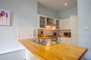 a kitchen with white cabinets and a wooden counter top at Modern, Light-filled and Sleek West End Apartment in Glasgow