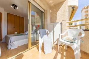 a room with a bed and two white chairs at Apartamentos Córdoba Arysal in Salou