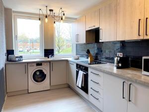 a kitchen with white cabinets and a washer and dryer at Beautiful West End Flat with Private Parking in Glasgow