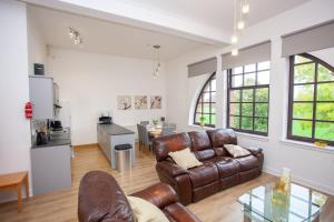 a living room with a leather couch and a kitchen at Glasgow Green Getaway with Free Parking in Glasgow