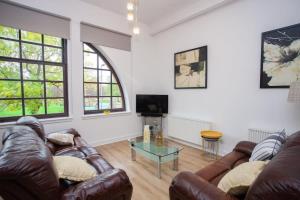 a living room with two leather couches and a tv at Glasgow Green Getaway with Free Parking in Glasgow