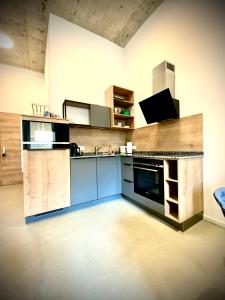 a large kitchen with blue cabinets and a tv at WATERFRONT - Urbane Eleganz am Bachufer in Villach