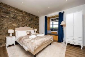 - une chambre avec un mur en pierre et un lit dans l'établissement Blar Cottage (Private Sauna + Fast Starlink Wifi), à Hayfield