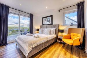 a bedroom with a large bed and a yellow chair at New Build Lodge With Stunning Views of Loch Awe in Hayfield