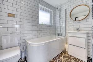 Baño blanco con bañera, lavabo y espejo en New Build Lodge With Stunning Views of Loch Awe, en Hayfield