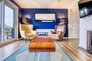 sala de estar con paredes azules y mesa de centro de madera. en New Build Lodge With Stunning Views of Loch Awe, en Hayfield