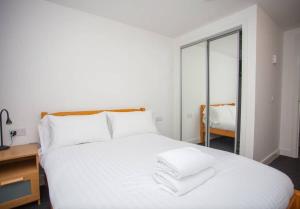 uma cama branca com lençóis brancos e almofadas em Beautiful Flat with Panoramic Views over the City em Glasgow