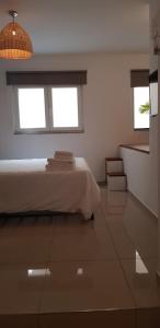 a white bedroom with a bed and two windows at Bright & modern studio,Sliema in Sliema