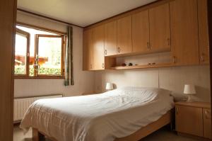 een slaapkamer met een bed, houten kasten en een raam bij Camping Boslust, Bungalow de Koekoek in Putten