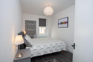 een kleine slaapkamer met een bed en een lamp bij Newly Renovated City Apartment in Glasgow