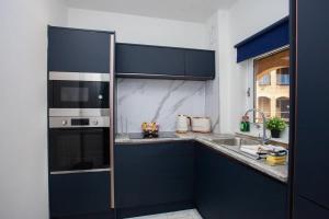 een keuken met blauwe kasten en een roestvrijstalen apparaat bij Newly Renovated City Apartment in Glasgow