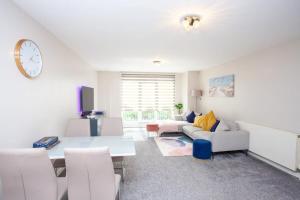 uma sala de estar com um sofá, uma mesa e um relógio em Stunning 3 Bed Apartment em Bearsden