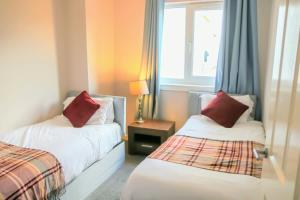 貝爾斯登的住宿－Stunning 3 Bed Apartment，酒店客房设有两张床和窗户。