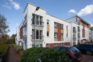 a white building with cars parked in front of it at Stunning 3 Bed Apartment in Bearsden