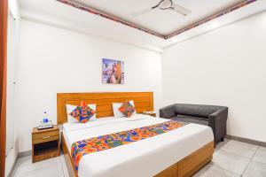 a bedroom with a bed and a chair in it at FabHotel Emoji Stays in Gurgaon