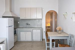 a kitchen with a table and a white refrigerator at Artemis Apartments in Tinos
