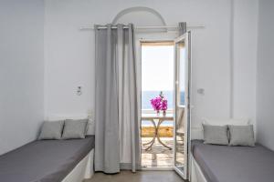 pokój z 2 łóżkami i stołem z oknem w obiekcie Artemis Apartments w mieście Tinos