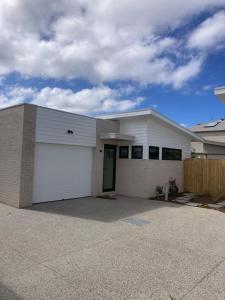 a white house with a large garage at Hamilton By the Bay 3 Newly Built in Safety Beach