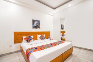 a white bedroom with a large bed with colorful pillows at FabHotel Emoji Stays in Gurgaon