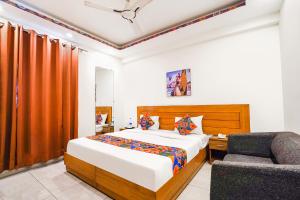 a bedroom with a bed and a chair at FabHotel Emoji Stays in Gurgaon