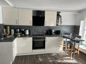 uma cozinha branca com armários brancos e uma mesa em Smart Home - Die etwas andere Ferienwohnung! em Brandenburg an der Havel