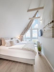 a white bedroom with two beds and a window at Ocean 3 in Rettin