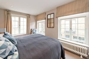 1 dormitorio con 1 cama grande y 2 ventanas en *Newly Renovated 2-Bed in Heart of Notting Hill*, en Londres